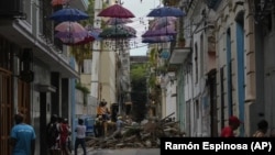 Personas observan a los bomberos retirar escombros de un edificio colapsado en la calle Lamparilla (La Habana), que dejó tres personas muertas. (AP /Ramón Espinosa/Archivo)